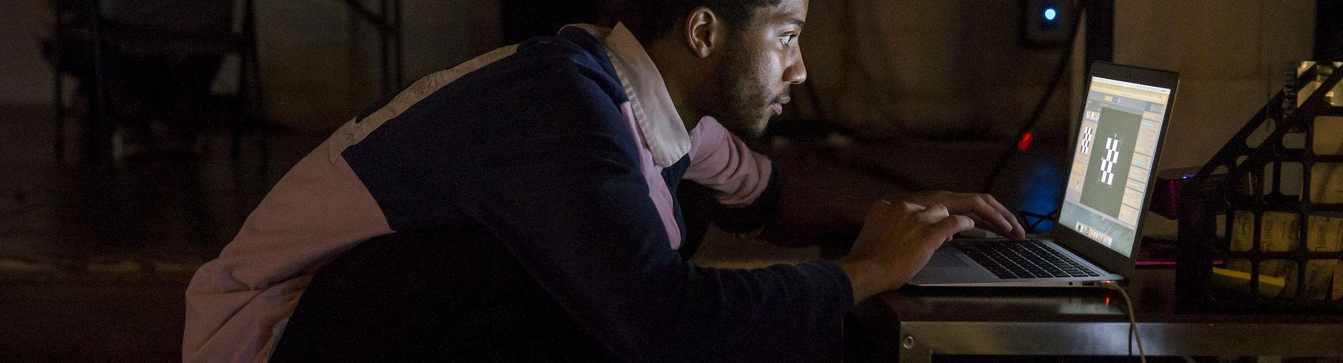 Student looking at a computer screen in a dark room.