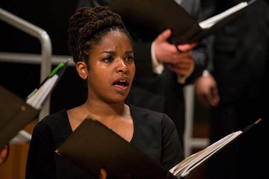 Choir singer holding musical score performing in a concert wearing black top