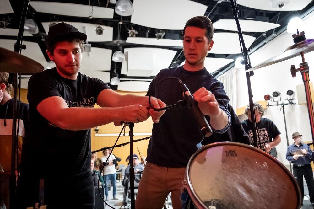 Two students set up microphones for a 音乐 recording session.